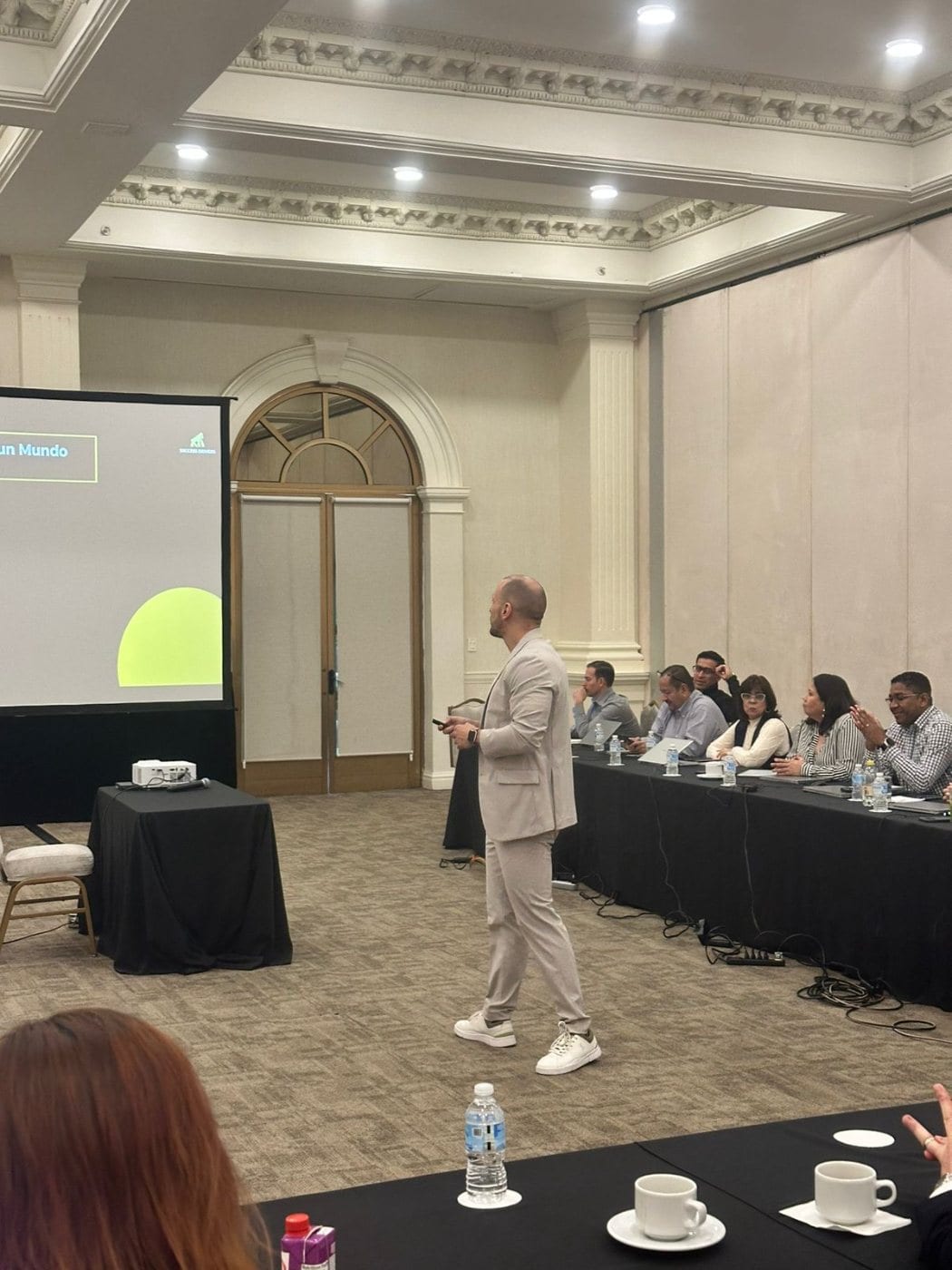 Christian presentando con traje claro en un salón